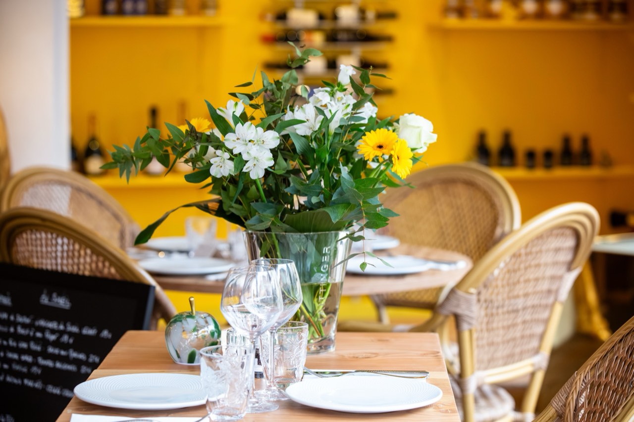 Salle du restaurant avec bouquet de fleurs et étagères de vins